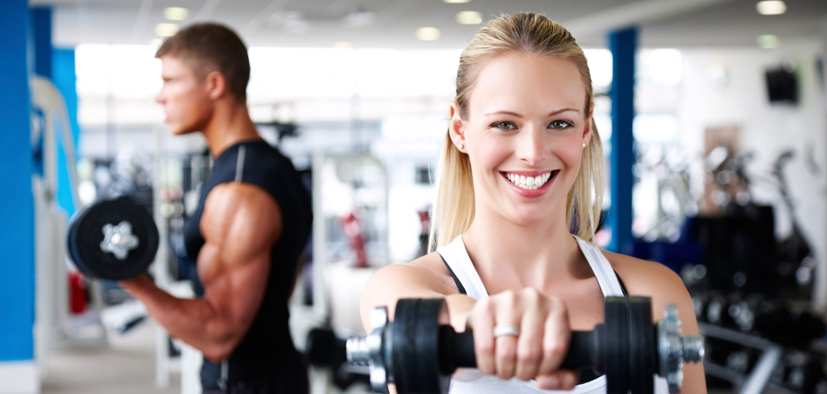 Woman exercising with dumbbells in a gym.