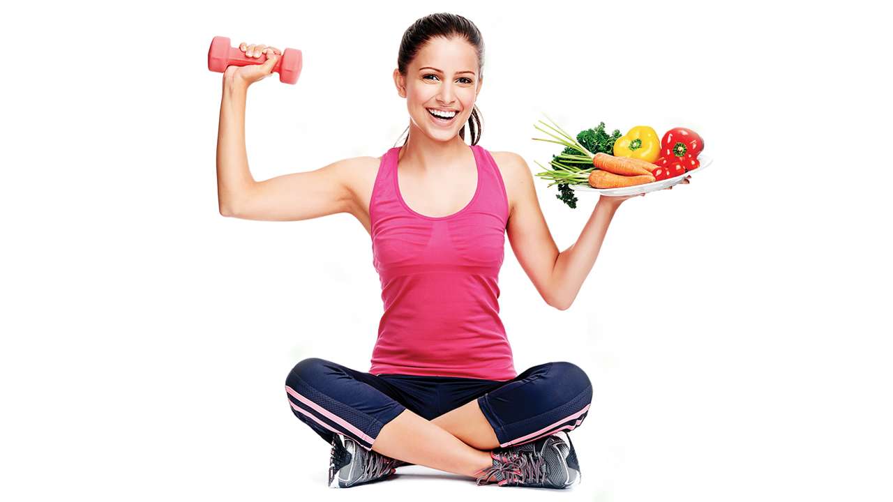 woman holding dumbbell in one hand, and a salad plate in the other.