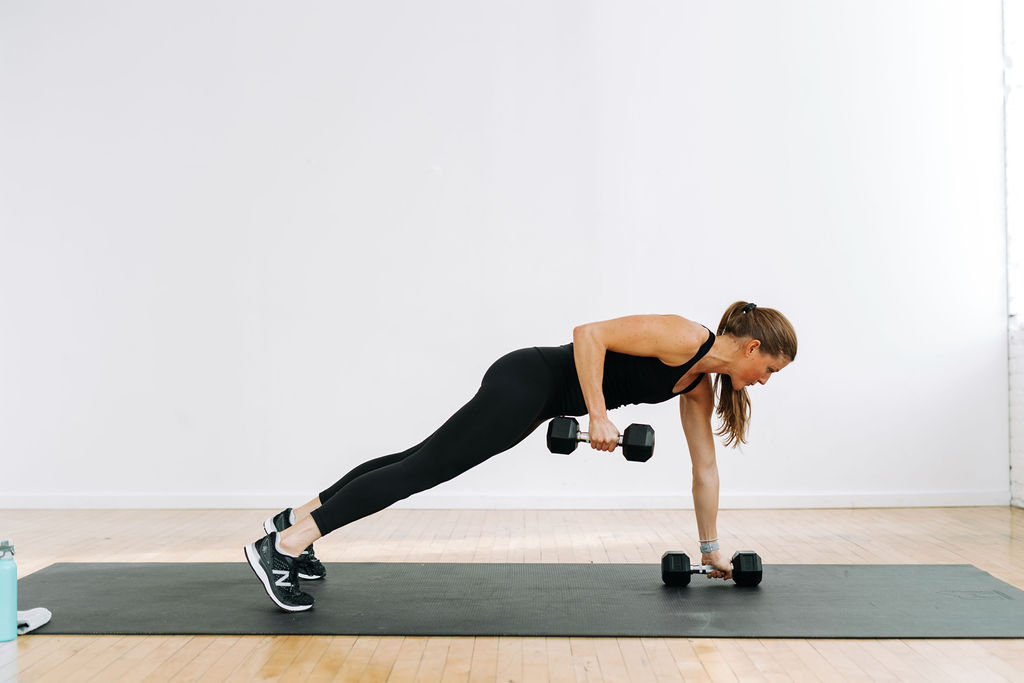 Woman with barbells doing pushups.