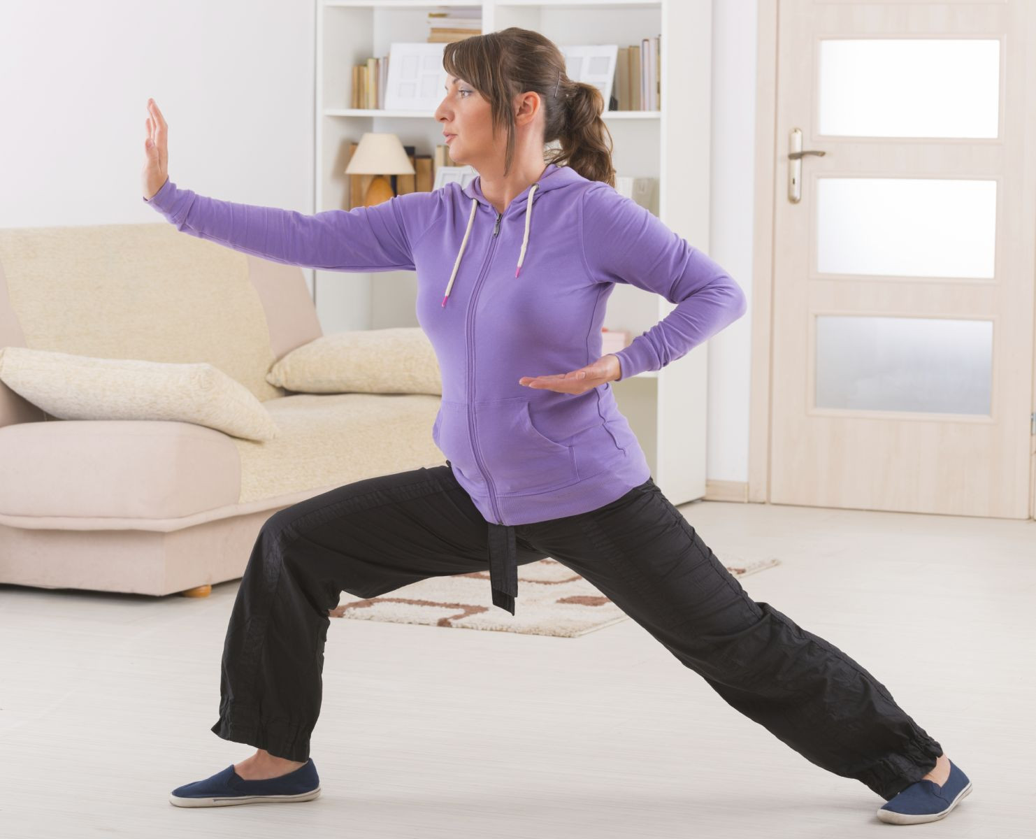 Woman demonstrating tai chi in her living roon.