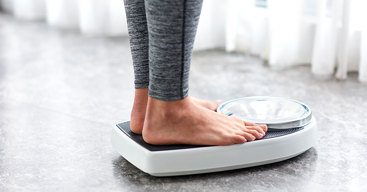 Woman on a weight scale in bathroom.