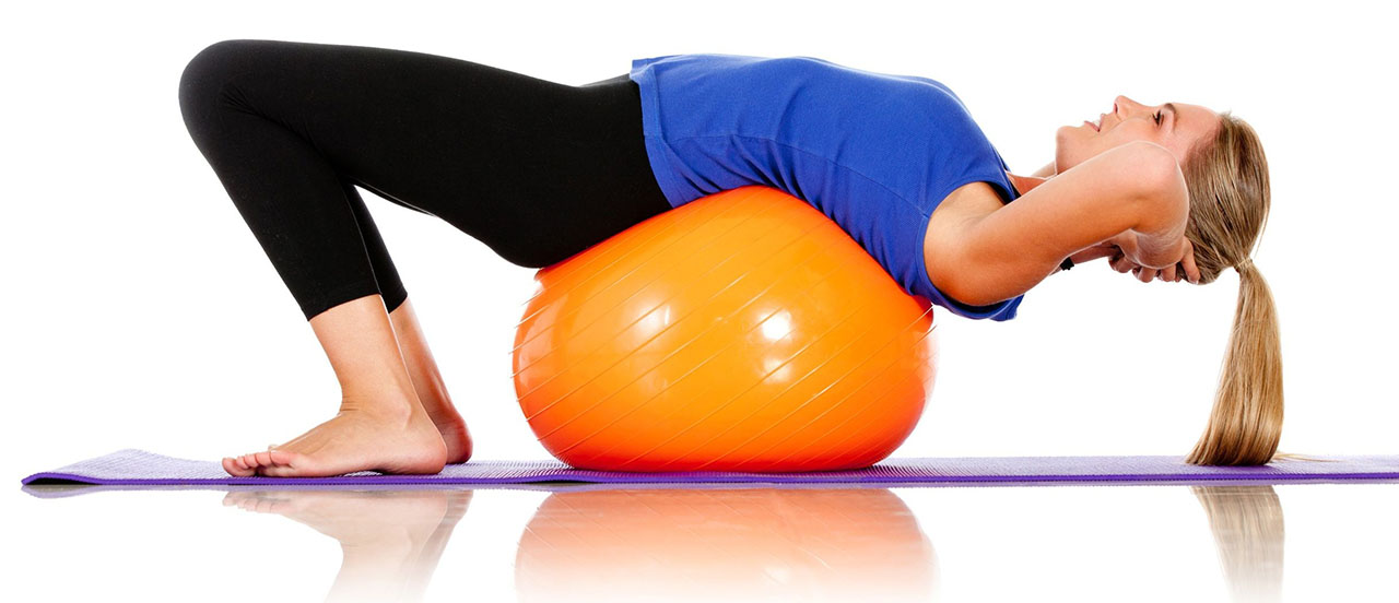 Woman doing Pilates using exercise ball.