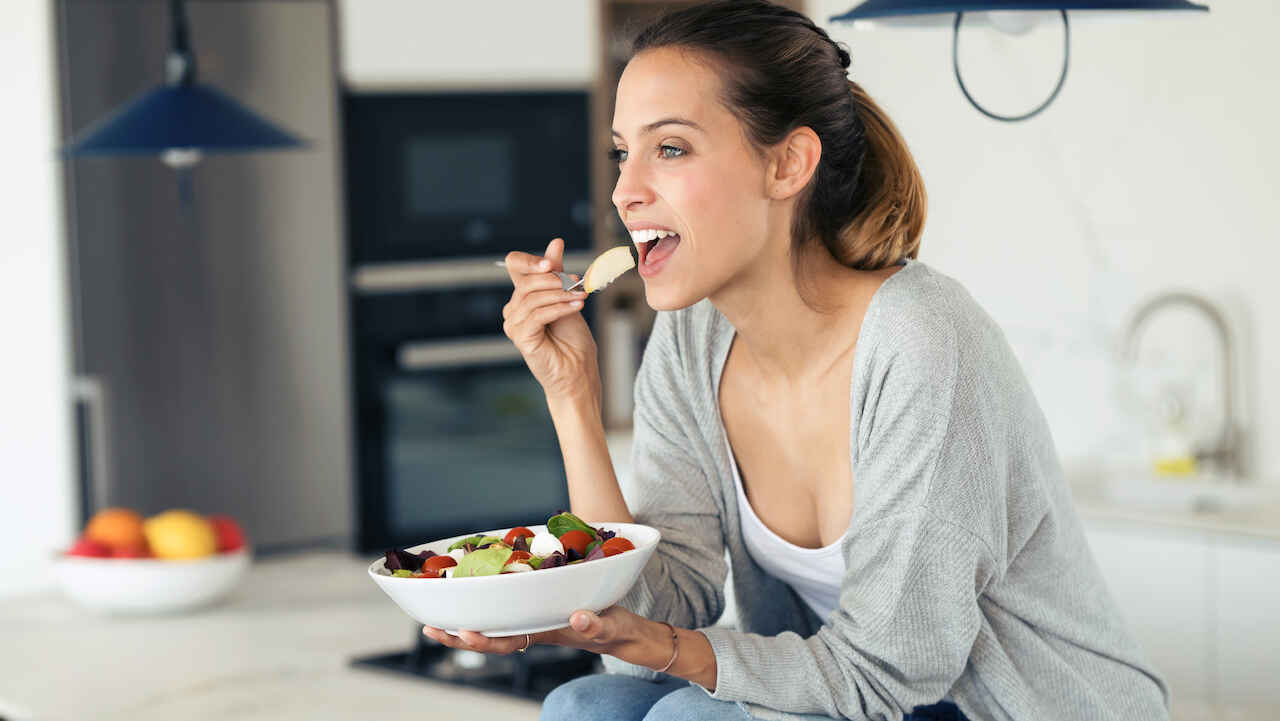 Woman eating from a bowl of fruit.