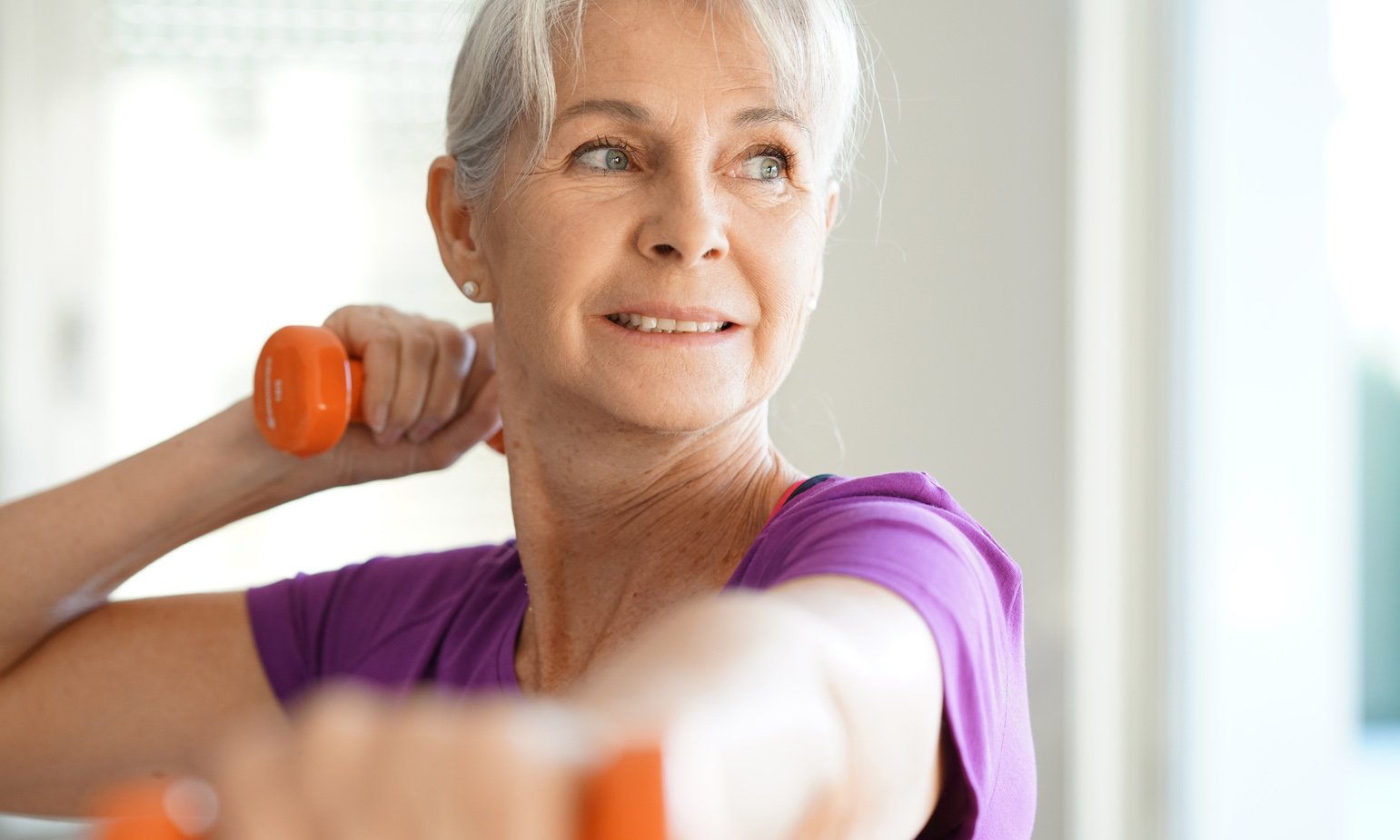 Older woman exercising using dumbbells.