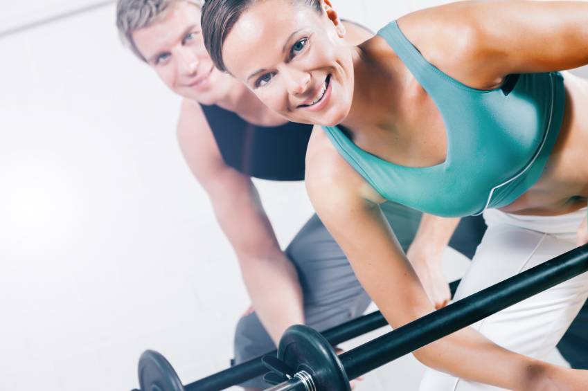 Couple exercising with barbells to maintain muscle mass.