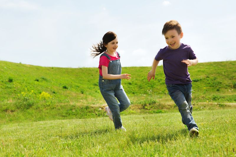 Kids running in a field of grass.