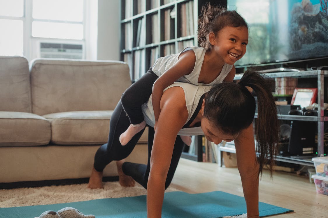 Woman doing a pushup with a child on her back