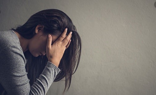 Woman with hands covering her face.