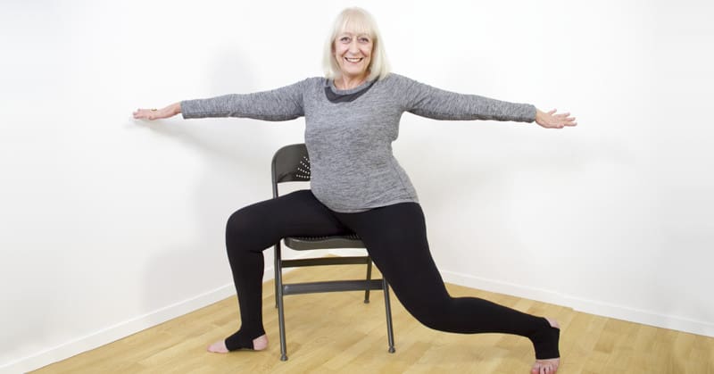 Lady doing exercises sitting in a chair.