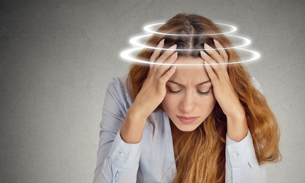 Young woman with hands on her head because of vertigo.